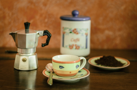 composition with a cup of coffee and what is needed to prepare coffee in the traditional way, on an antique wooden piece of furniture in natural lightの写真素材