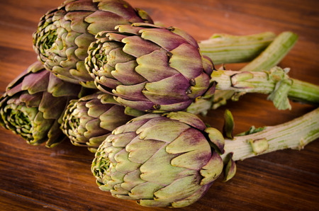 composition of raw artichokes on a brown wooden tableの写真素材