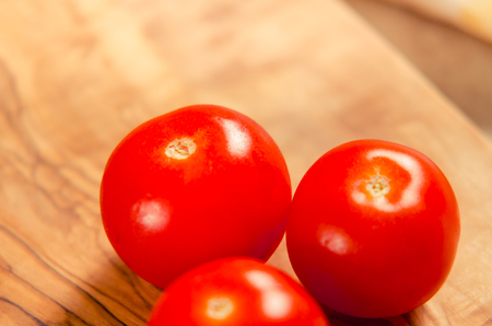 ciligino tomatoes on olive wood cutting board with napkin and cutlery on white tableの写真素材