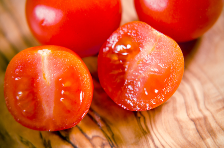 ciligino tomatoes on olive wood cutting board with napkin and cutlery on white tableの写真素材