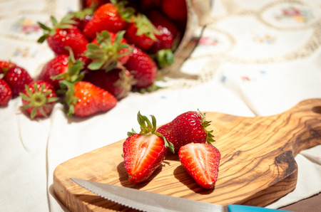 fresh strawberries cut on an olive wood cutting boardの写真素材