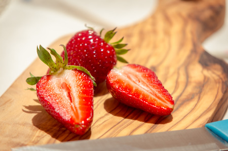 fresh strawberries cut on an olive wood cutting boardの写真素材