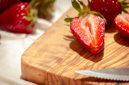 fresh strawberries cut on an olive wood cutting boardの写真素材