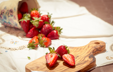 fresh strawberries cut on an olive wood cutting boardの写真素材