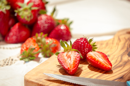 fresh strawberries cut on an olive wood cutting boardの写真素材
