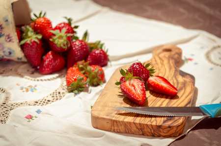 fresh strawberries cut on an olive wood cutting boardの写真素材