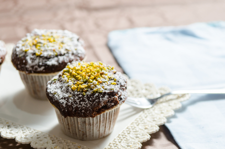 chocolate muffin with powdered sugar and pistachio grainの写真素材