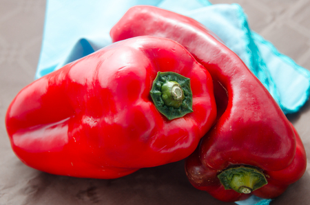 composition of red peppers on brown background and blue napkinの写真素材
