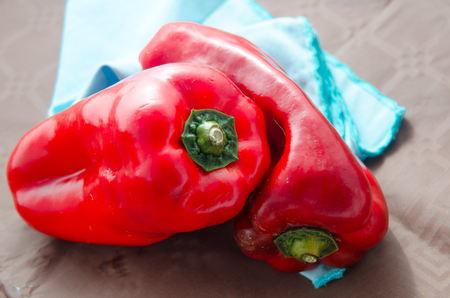 composition of red peppers on brown background and blue napkinの写真素材