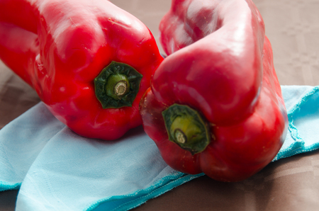 composition of red peppers on brown background and blue napkinの写真素材