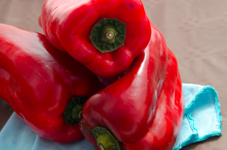 composition of red peppers on brown background and blue napkinの写真素材