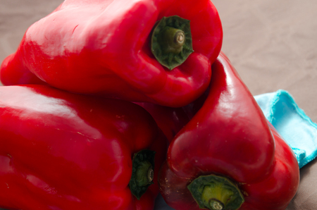 composition of red peppers on brown background and blue napkinの写真素材