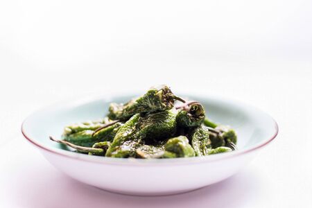 A plate of green peppers on a white backgroundの写真素材