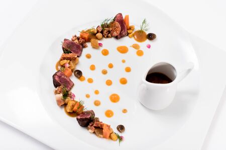 A plate of meat, vegetables and sauceの写真素材