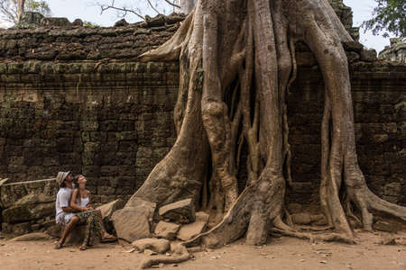 Beautiful Couple looking at Giant Roots at Angkor Wat Cambodia. Traveling Asia Adventure. Incredible Journey.の写真素材
