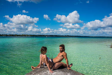 Bacalar Lake at Riviera MAya, Quinatana Roo. Couple sitting on a dock contemplating. Water motion.の写真素材
