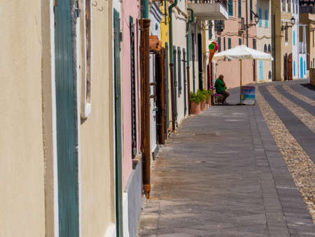 ALGHERO, ITALY - JULY 21, 2016 - Summer view of the seafront in the old town, with an unidentified man sitting in the shadow.のeditorial素材