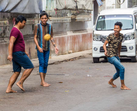 YANGON, MYANMAR - JANUARY 4, 2018: Burmese guys playing football on a street in the city center.のeditorial素材
