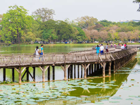 YANGON, MYANMAR - JANUARY 2, 2018: People on the wooden bridge on the Kandawgyi Lake.のeditorial素材