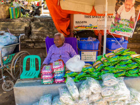 BAGAN, MYANMAR - JANUARY 5, 2018: Old woman selling the "Bagan's Tamarind Flake", the secret to live a long life.のeditorial素材