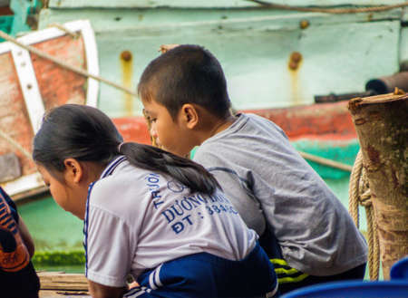 PHU QUOC, VIETNAM - FEBRUARY 8, 2018: Vietnamese kids sitting on the pier of the Duong Dong port.のeditorial素材