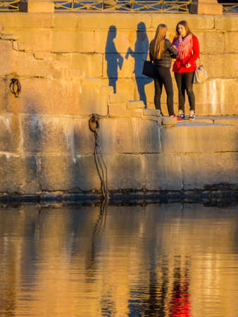 ST. PETERSBURG, RUSSIA - APRIL 13, 2018: Young girls on the embankment of the Moyka River at sunset.のeditorial素材