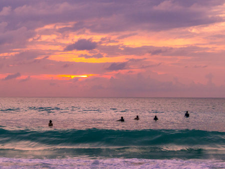 Surfers waiting to catch a wave at sunset in Dreamland Beach, Bali, Indonesia