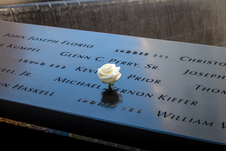 Birthday white rose left near name of the victim engraved on bronze parapet of 9/11 Memorial at Ground Zero World Trade Center - New York City, USAのeditorial素材