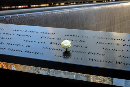 Birthday white rose left near name of the victim engraved on bronze parapet of 9/11 Memorial at Ground Zero World Trade Center - New York City, USAのeditorial素材