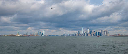 Panoramic view of Lower Manhattan skyline and Libery Island and Liberty Statue - New York, USAの写真素材