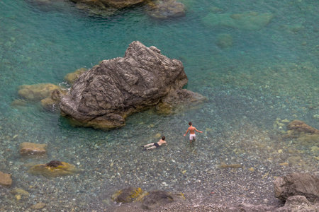 Boys playing in the water at a Mediterranean rocky beach of Ionian Sea - Bova Marina, Calabria, Italyのeditorial素材