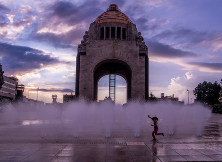 Girl playing with the water fountain in front of Monument to the Mexican Revolution (Monument to the Revolution) - Mexico City, Mexicoのeditorial素材