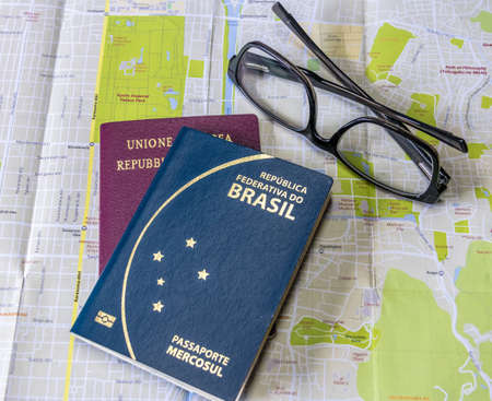 Planning a trip - Brazilian and Italian passports on city map with glassesの写真素材