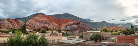 Panoramic view of Purmamarca town with the Hill of Seven Colors (Cerro de los siete colores) on background  - Purmamarca, Jujuy, Argentinaの写真素材