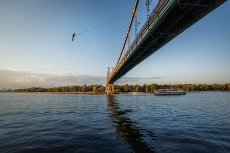 Man Bungee Jumping on Parkovy pedestrian bridge over Dnieper River - Kiev, Ukraineの写真素材