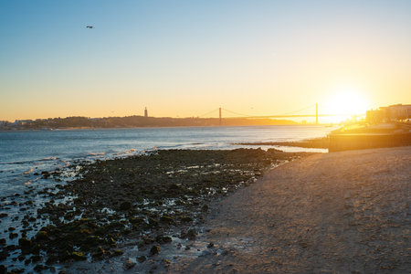 Tagus River (Rio Tejo) at sunset with 25 de Abril Bridge and Sanctuary of Christ the King skyline on background - Lisbon, Portugalの写真素材