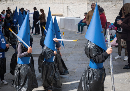 Arcos de la Frontera, Spain - Apr 10, 2019: Kids with cloaks and hoods (Capirotes) at Holy Week Procession (Semana Santa) - Arcos de la Frontera, Cadiz, Spainのeditorial素材