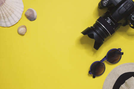 Summer Accessories for the traveler on yellow background copy space are a digital camera, hat, flat lay concep of summer holiday and shellsの写真素材