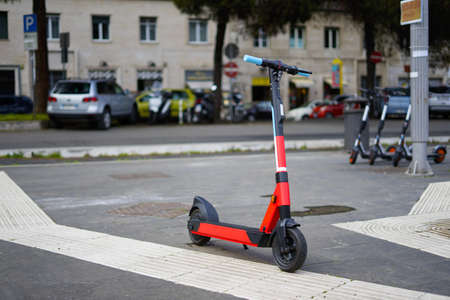 Rental electric scooter parked on the side walk on a rainy day