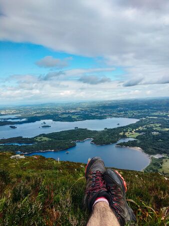 Unrecognizable man resting on the top of a mountain contemplating the landscapeの写真素材