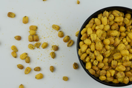 Roasted corn with mustard and honey in the black bowl. Top view on the white background.