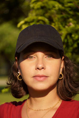 Young girl in black cap and red t-shirt in the park at sunset. Sunny day and open countryside with...