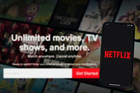 Netflix app on the smartphone screen with the blurred television home screen in the background....