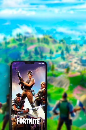 Fortnite game app on the smartphone screen with the game screen blurred in the background. Rio de...