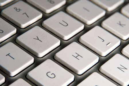 Computer keyboard with white keys and silver metallic structure. Some letters of the alphabet. Macro photography. Selective focus.の写真素材