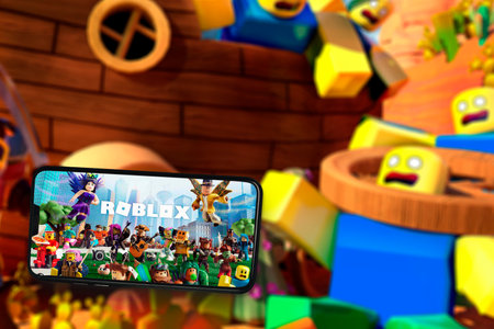 Roblox game app on the smartphone screen with the game screen blurred in the background. Rio de Janeiro, RJ, Brazil. May 2021.のeditorial素材