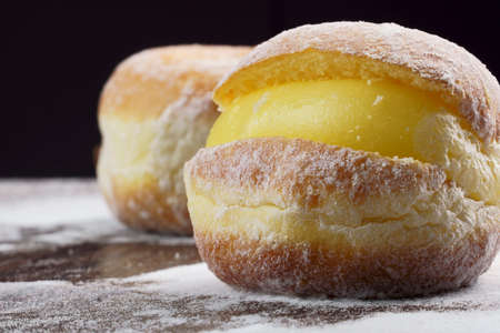 Berlin balls, known as Sonho in Brazil on wooden table with scattered icing sugar. It consists of a...