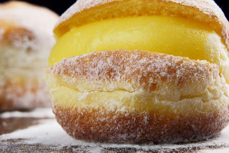 Berlin balls, known as Sonho in Brazil on wooden table with scattered icing sugar. It consists of a...