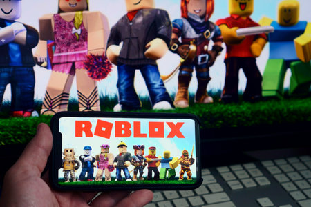Roblox game app on the smartphone screen with the game screen blurred in the background. Rio de Janeiro, RJ, Brazil. May 2021.のeditorial素材