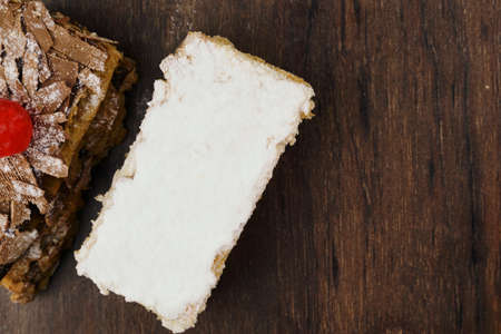 Puff pastry cakes with powdered sugar and cream and another with chocolate and a cherry on top on...